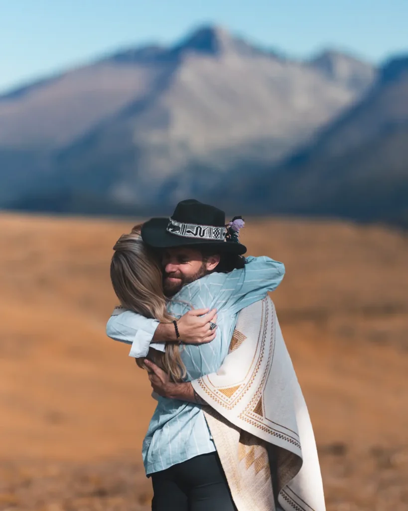 Hombre y mujer abrazándose con una montaña en el fondo